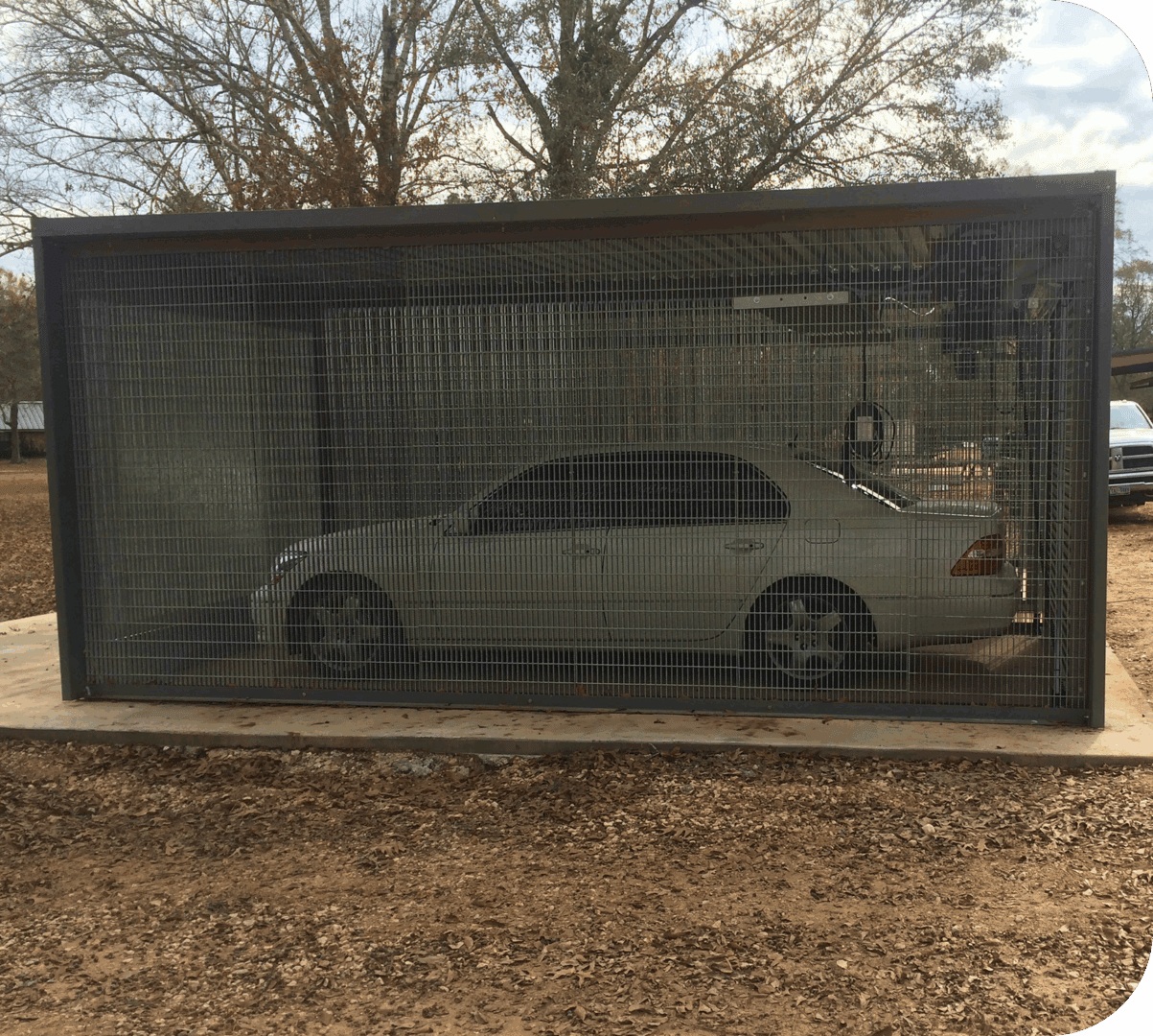 Car enclosed in a metal cage outdoors.